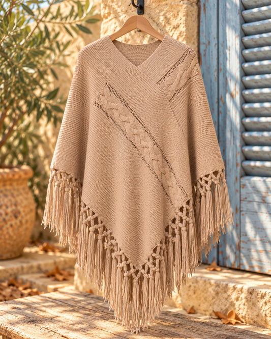 Poncho cerrado de punto con escote en V y flecos en color beige, vista del producto en percha.