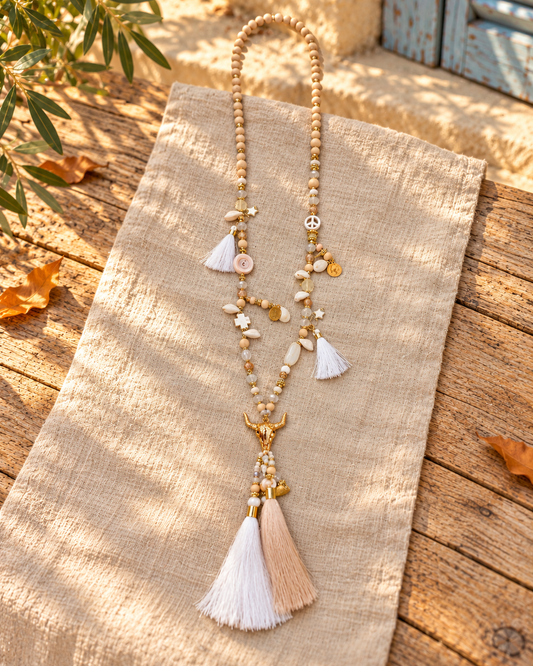 Collar largo boho calavera de toro · blanco y dorado, bodegón sobre tejido claro