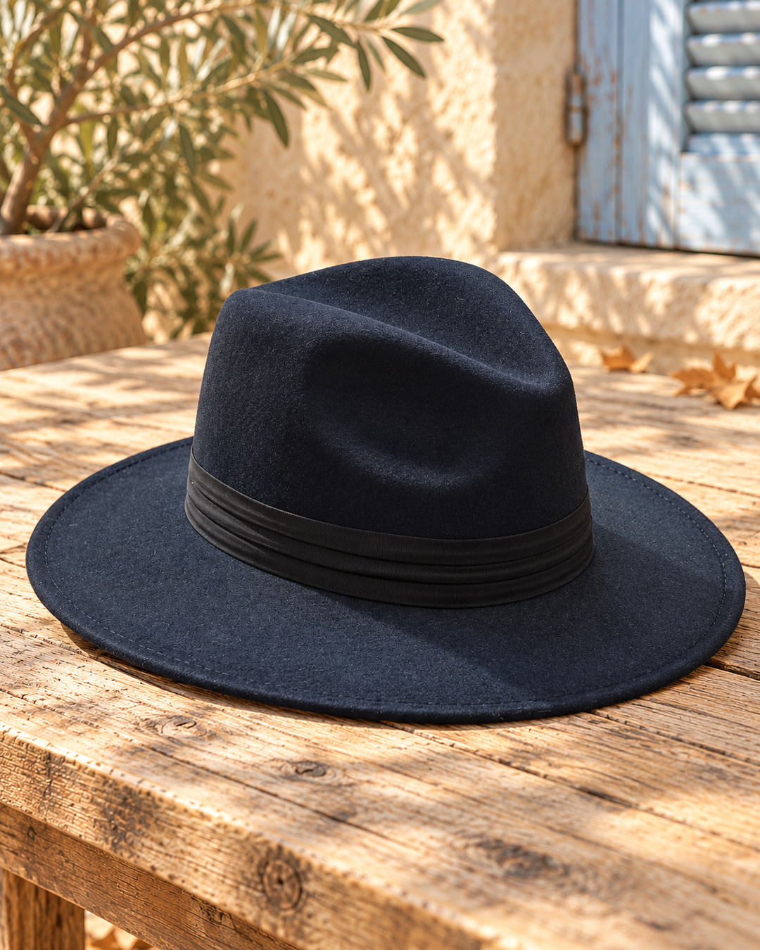 Sombrero fedora boho azul oscuro con cinta, bodegón del producto sobre madera